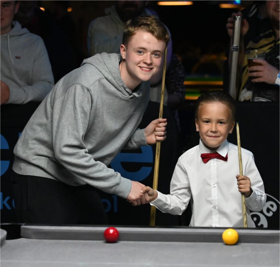 Two junior players shaking hands across the table before a frame